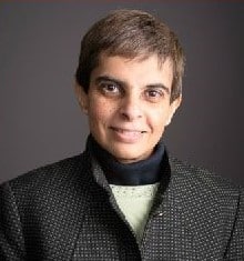 Person in dark jacket, neutral background.