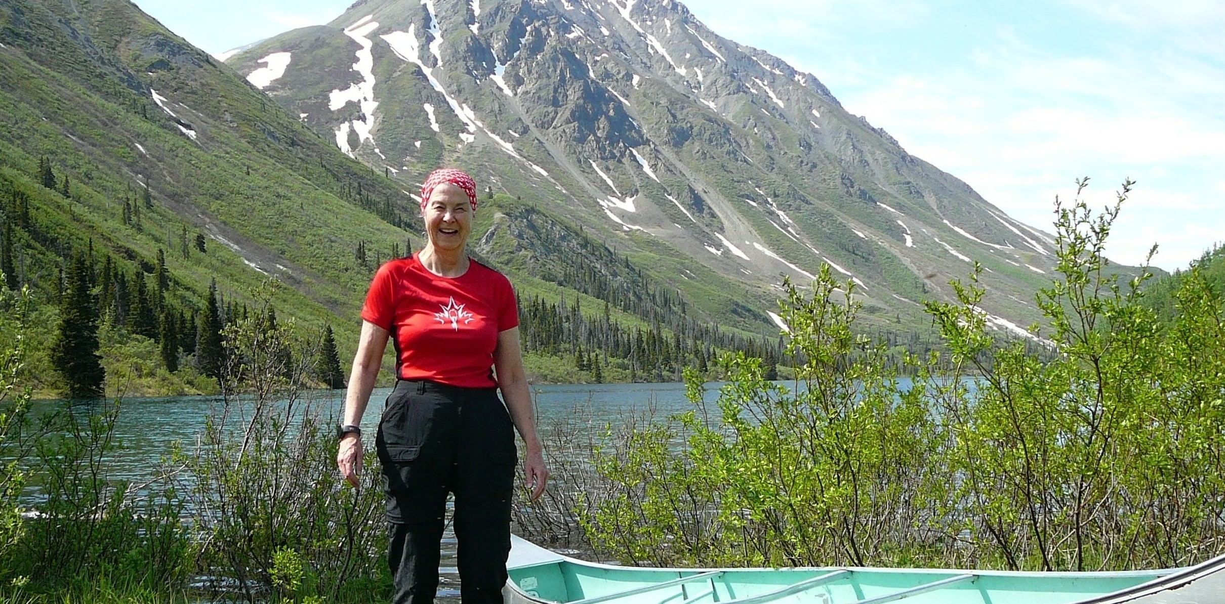 Person by lake with mountains behind