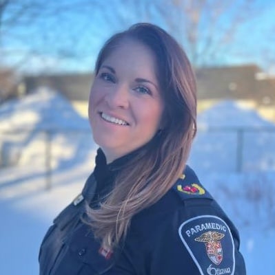 Person in paramedic uniform outdoors.