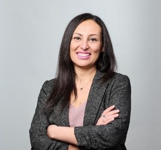 Woman in professional attire, arms crossed.