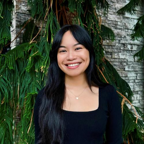 Person standing in front of greenery.