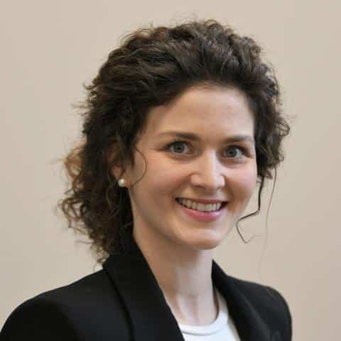 Person with curly hair, wearing blazer.