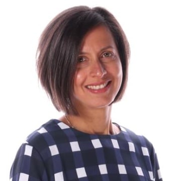 Woman in checkered blouse, neutral background.