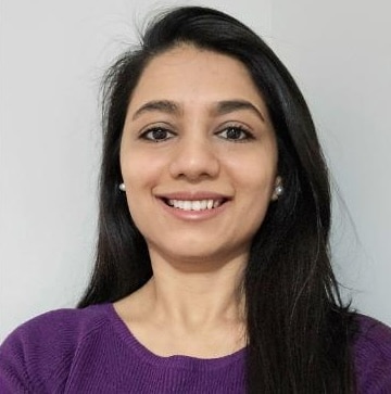 Person wearing purple sweater, neutral background.