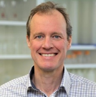 Man in checkered shirt, neutral background.