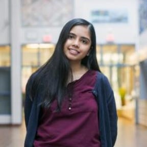Person standing indoors with long hair.